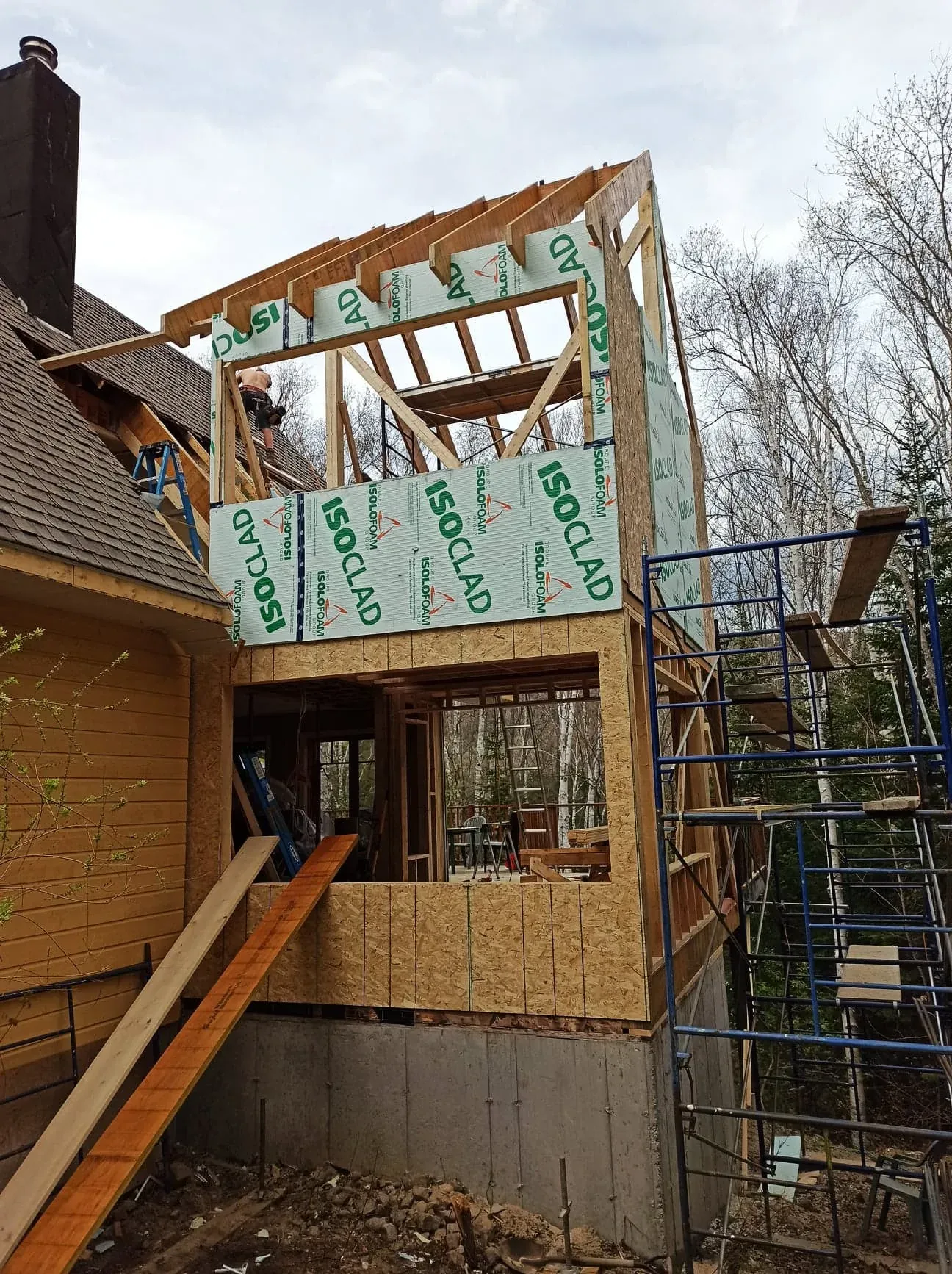 Étage ajouté sur une maison existante, murs couverts de panneaux isolants, échafaudage monté sur le côté
