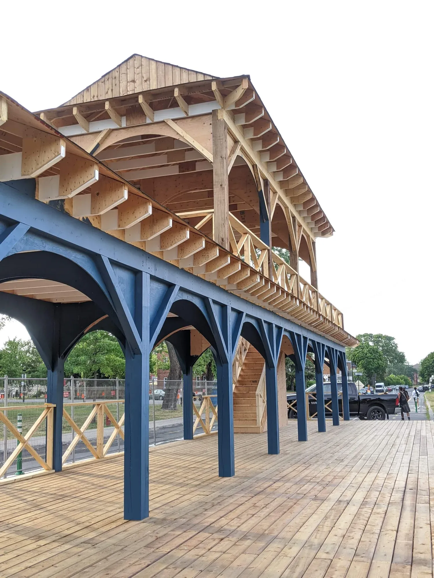 Halle publique de bois à deux niveaux, colonnes peintes et aisseliers courbes soutenant la galerie, plancher de bois neuf
