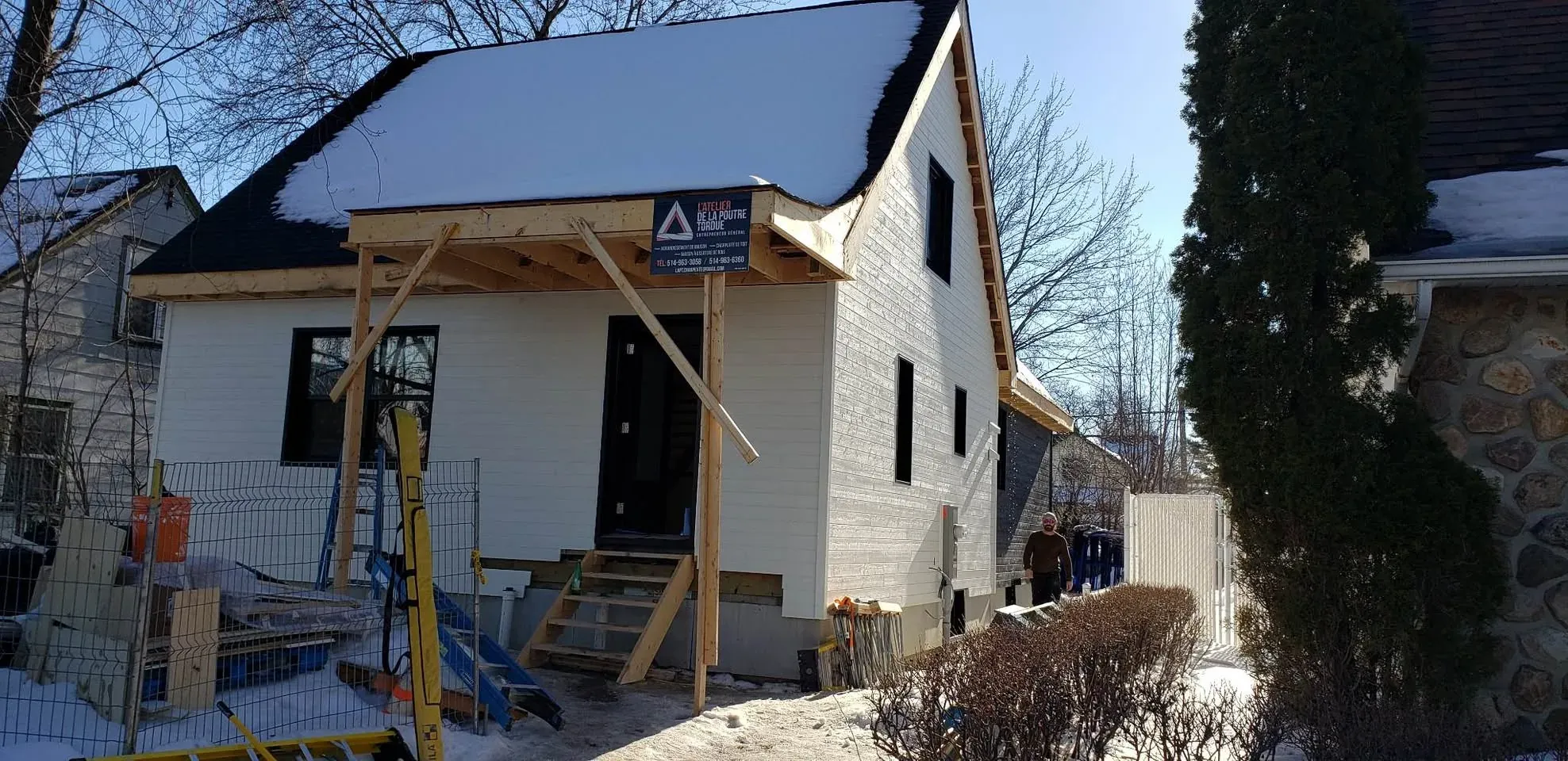 Maison blanche dont la façade vient d'être refaite, avec un auvent de bois neuf monté au-dessus de la porte d'entrée