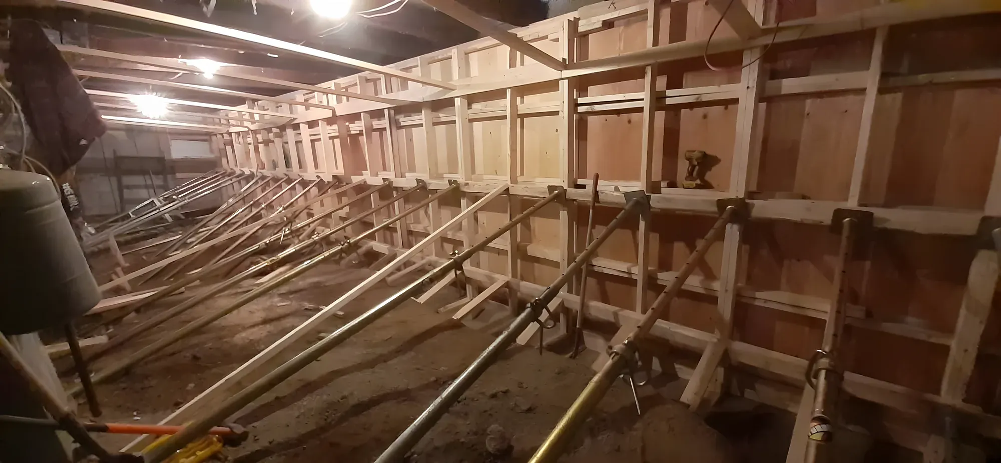 Coffrage de mur de fondation dans un sous-sol, retenu par une rangée d'étais métalliques posés en diagonale