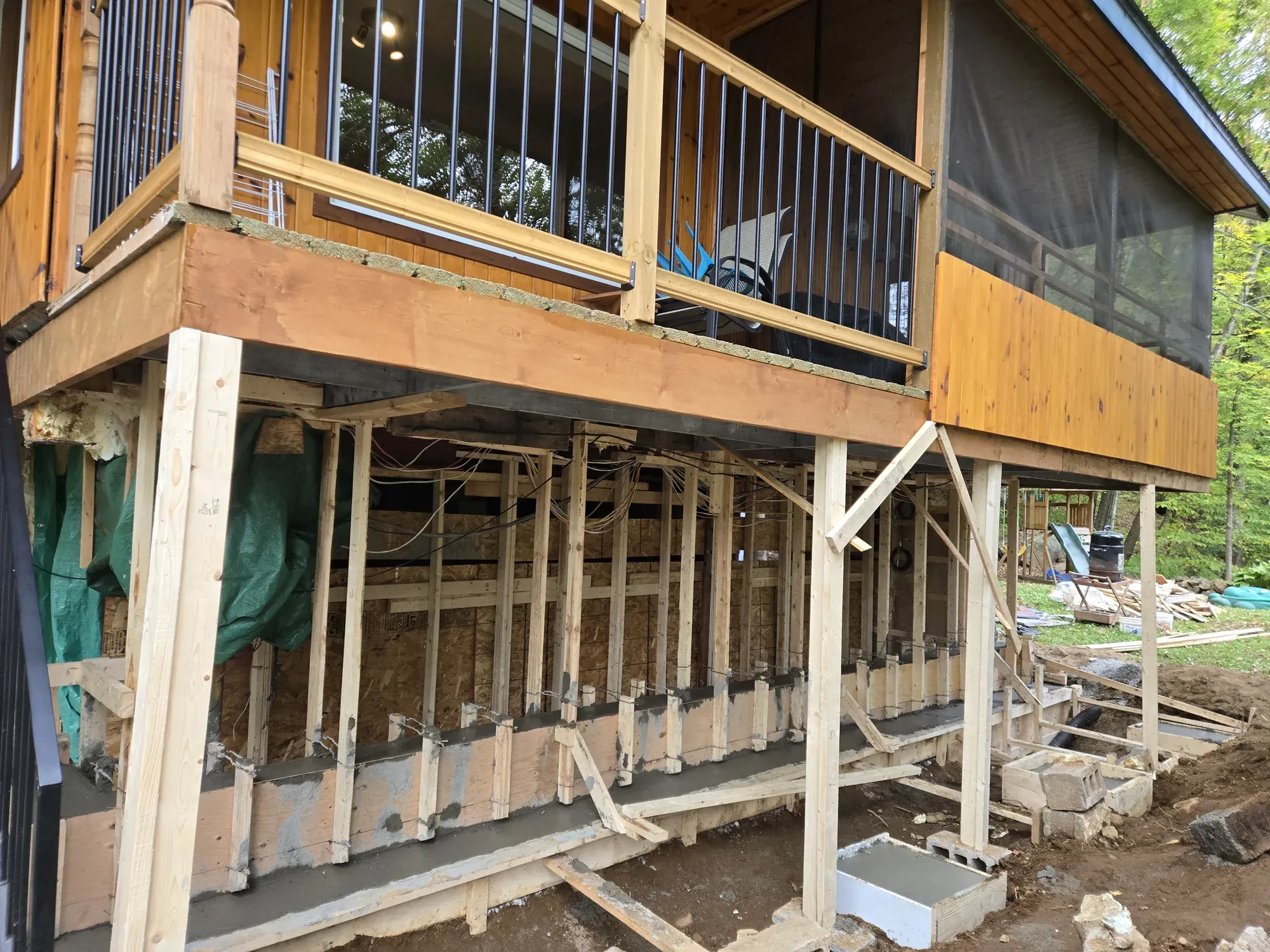 Fondation de béton neuve coulée sous une galerie, le bâtiment reposant sur des poteaux de bois pendant les travaux